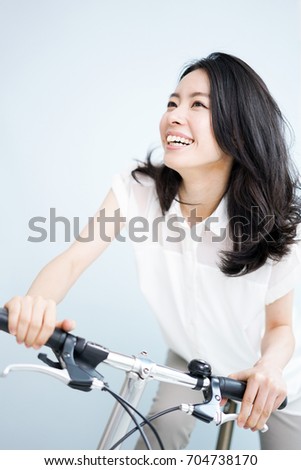 Beautiful young woman on bicycle against light blue background.