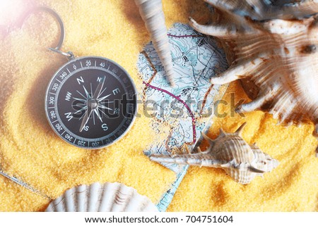 Compass on a yellow sand, assorted shells