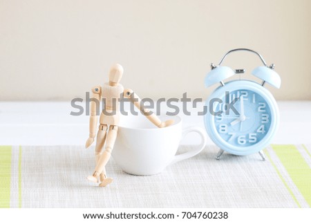 coffee cup with wood puppet model and blue alarm clock. Get ready go to work or go to study in the morning concept.