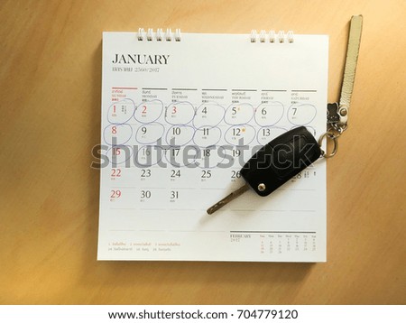 Car key on white Thai calendar on wood desk and made circle marked on date to mark appointment reminder of installment pay for car finance.