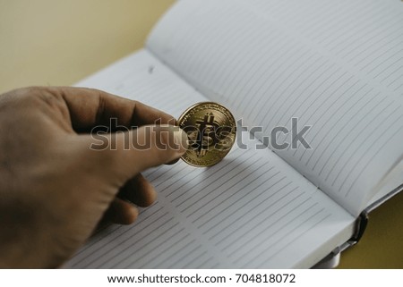 Golden bitcoin and note book in background