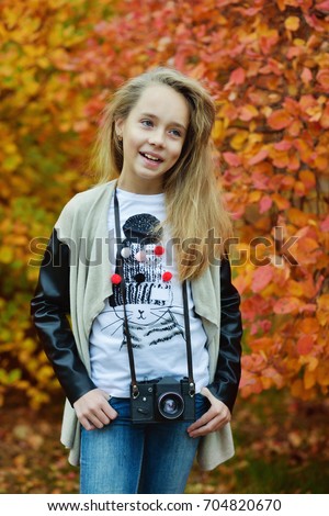 pretty preteen girl with old photocamera in fall time