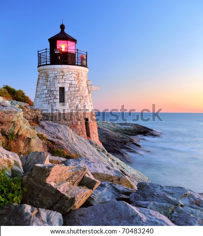 Beautiful old lighthouse on rocks at sunset Royalty-Free Stock Photo #70483240