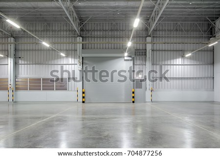 Roller door or roller shutter using for factory, warehouse or hangar. Industrial building interior consist of polished concrete floor and closed door for product display or industry background. Royalty-Free Stock Photo #704877256