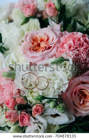 Two gold wedding rings on the background of a beautiful bouquet of roses and carnations