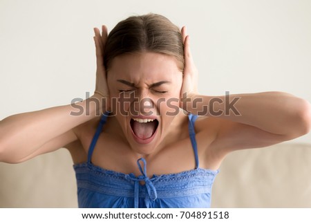 Portrait of stressed woman closing ears with hands and screaming with closed eyes. Hysterical lady feeling nervous breakdown, psychological problems, mood swing, fatigue and exhaustion, depression  Royalty-Free Stock Photo #704891518