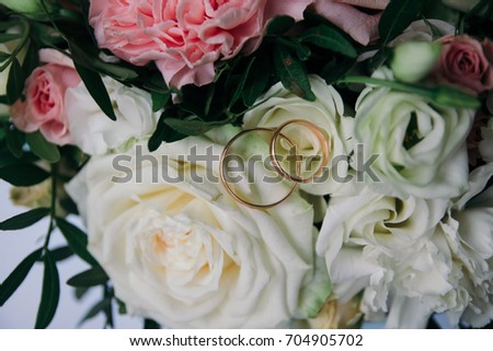 Two gold wedding rings on the background of a beautiful bouquet of roses and carnations