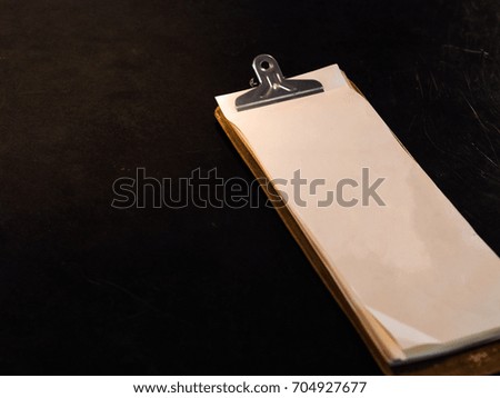 notepad with clipper on the black desk