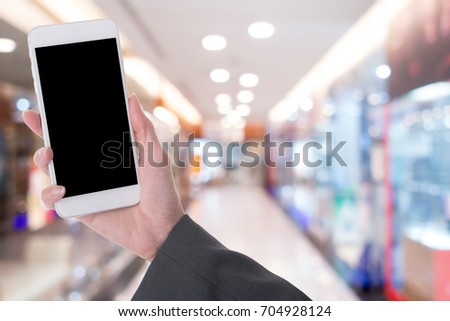 hand hold smart phone with image of shopping mall in background