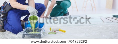 House painter pouring green wall paint into tray Royalty-Free Stock Photo #704928292