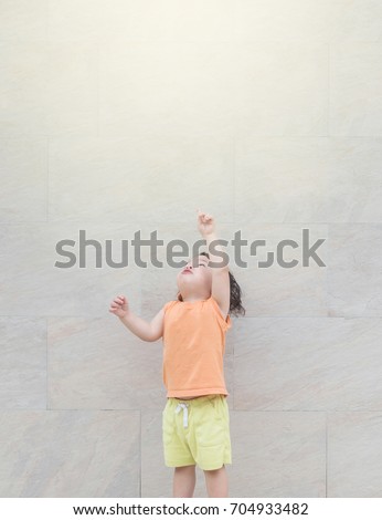 Closeup cute asian kid point to copy space of picture on marble stone wall textured background