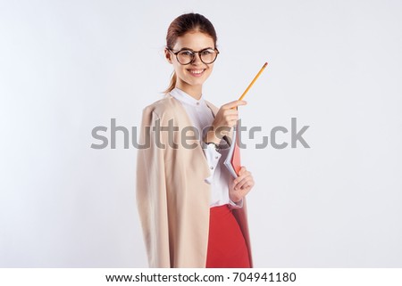 Woman teacher with glasses holds a folder tablet and looks into the camera room against a light background                               