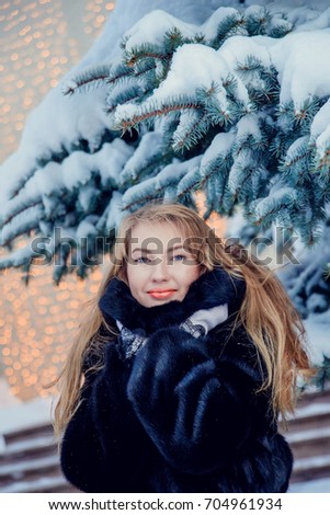 long-haired girl in a fur coat on the Christmas lights, snowy trees, winter walk