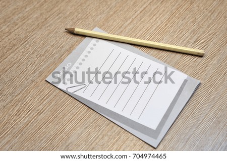 A memo pad and yellow pencil on wood office table. 