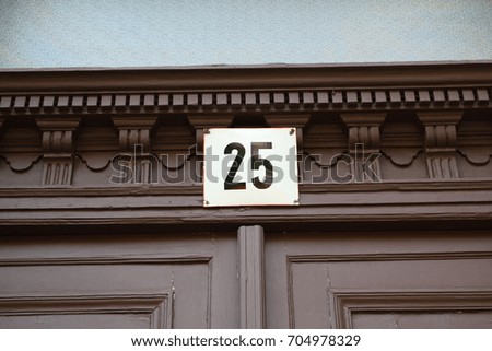 Number 25 sign, twenty-five written over an entrance door of a building.