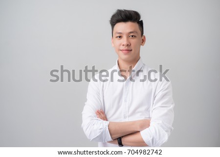 Portrait of good looking asian man over gray background. Royalty-Free Stock Photo #704982742