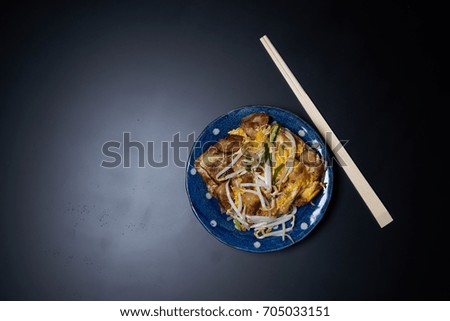 Thai style, turnip cake, sprouts, egg, chopsticks on black background