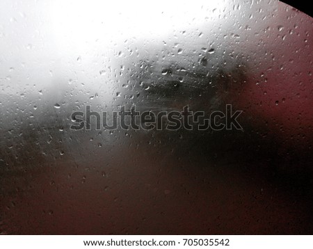 The Monsoon rain drops on the glass with heavy rain and cloud in background. 