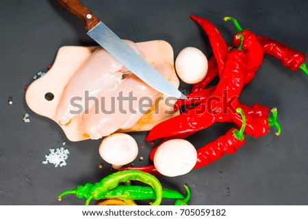 raw chicken wings with herbs in a transparent bowl Cauliflower with tomatoes and herbs and hot peppers with mushrooms on wooden background top view close up.