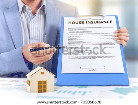 businessman show insurance policy with wooden home model