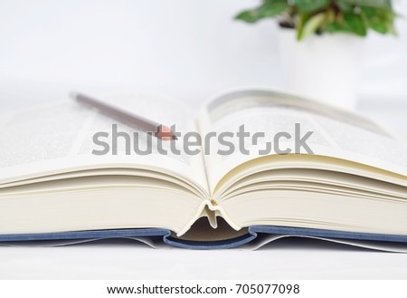 open book with black pencil on white table 