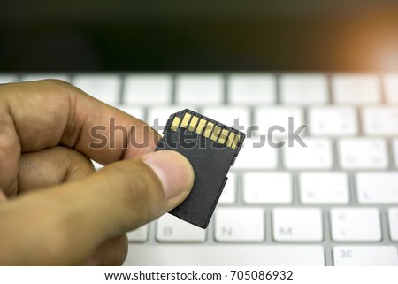 Backup file concept, Hand hold storage card on with keyboard, every photographer use external storage to backup picture at least two hard disk