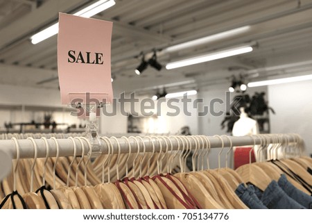 There is a sign that discount some clothes in the store. It is de-focused concept. 
/ Sale sign in the cloth store.