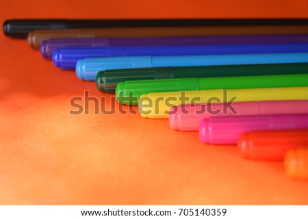 Assorted colorful makers on orange background focused on each colors