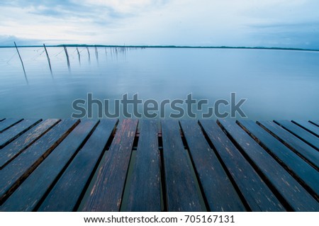 Wooden pier with water at morning of rainy day.