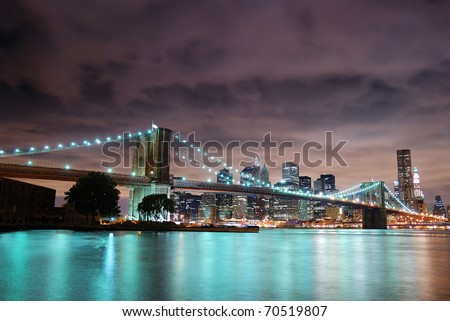 New York City Manhattan panorama view with Brooklyn Bridge at night with office building skyscrapers skyline illuminated over Hudson Rive