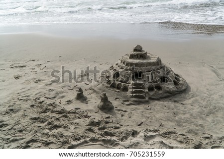 A slightly eroded sand castle sits on a wet beach. Concept for travel or vacation.