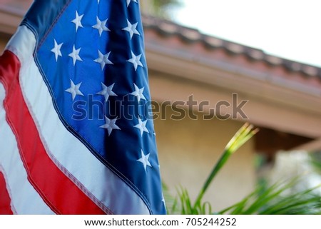 Landscape oriented picture with american flag hanging on the front porch of a home