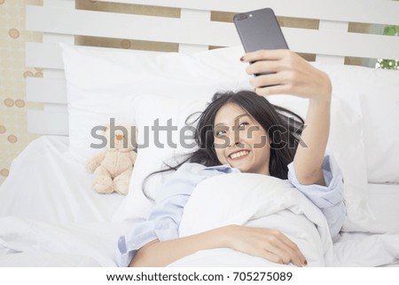 Beautiful young asian woman using smartphone for selfie on the bed, 20s year old.