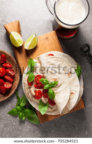 Home tortilla with hummus of white beans and beer on a gray stone table. Italian, Mediterranean style. With tomatoes and basil . dark beer
