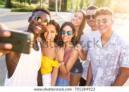 Portrait of group of young hipster friends using smart phone in an urban area.