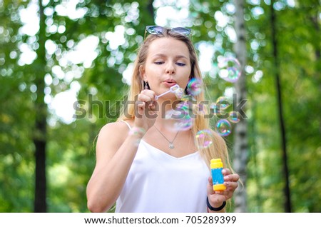 Young and beautiful girl lets bubbles in the park