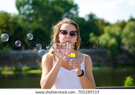 Young and beautiful girl lets bubbles in the park