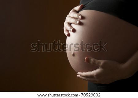 pregnant woman caressing  her belly with orange background Royalty-Free Stock Photo #70529002
