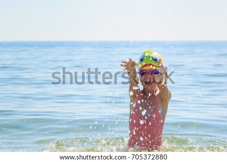 A girl in a hat and glasses for swimming is at sea.