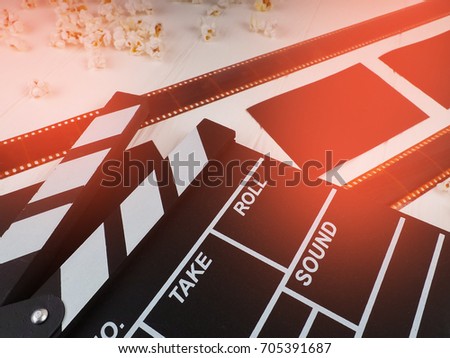 the film in the spiral, near the popcorn, Clapperboard copy space for text, fashion highlights in the photo, concept, film industry, film, abstract composition of movie, on a white background