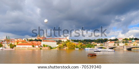 Panoramic view on Old Prague across Vltava river; early autumn; sunlit old roofs under dramatic skies
