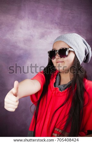 Teen girl, hipster shows thumbs up and smiles.