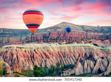Flying on the balloons early morning in Cappadocia. Colorful spring sunrise in Red Rose valley, Goreme village location, Turkey, Asia. Traveling concept background.