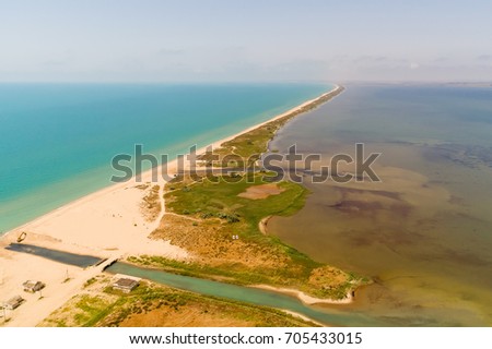 Drone aerial view of the long sand spit separates the sea with camping on the beach. Aerial view of the Sandy spit dividing the water of two colors. Sea and liman, firth at Russian south.