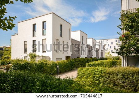 Modern townhouses in a residential area, new apartment buildings with green outdoor facilities in the city Royalty-Free Stock Photo #705444817