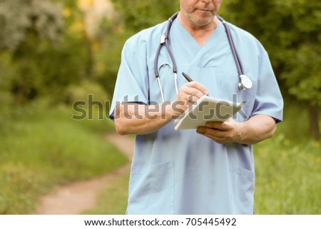 Doctor and nature concept. THE DOCTOR KEEPS MARKER IN THE HAND OVER THE UNIT IN THE PARK ON THE NATURE. Photo horizontal for your design.