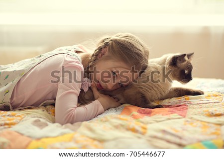 cute girl with pigtails plays with a cat