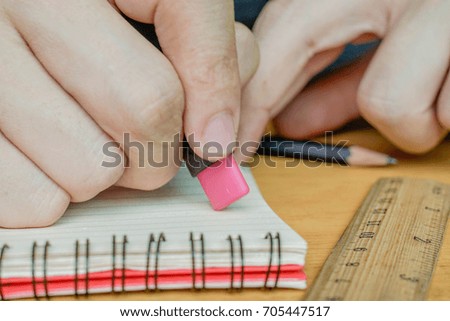 Hand hold a rubber to erase miss word on the notebook.
