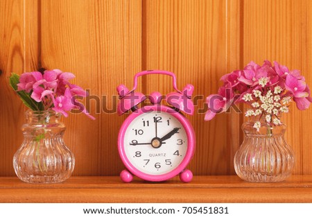 Pink Retro,vintage alarm clock with flowers on table background.