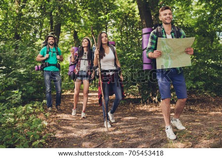 Four best friends are walking in autumn  forest, amazed by the beauty of nature, wearing comfortable outfits for hiking, sneakers, hats, have backpacks